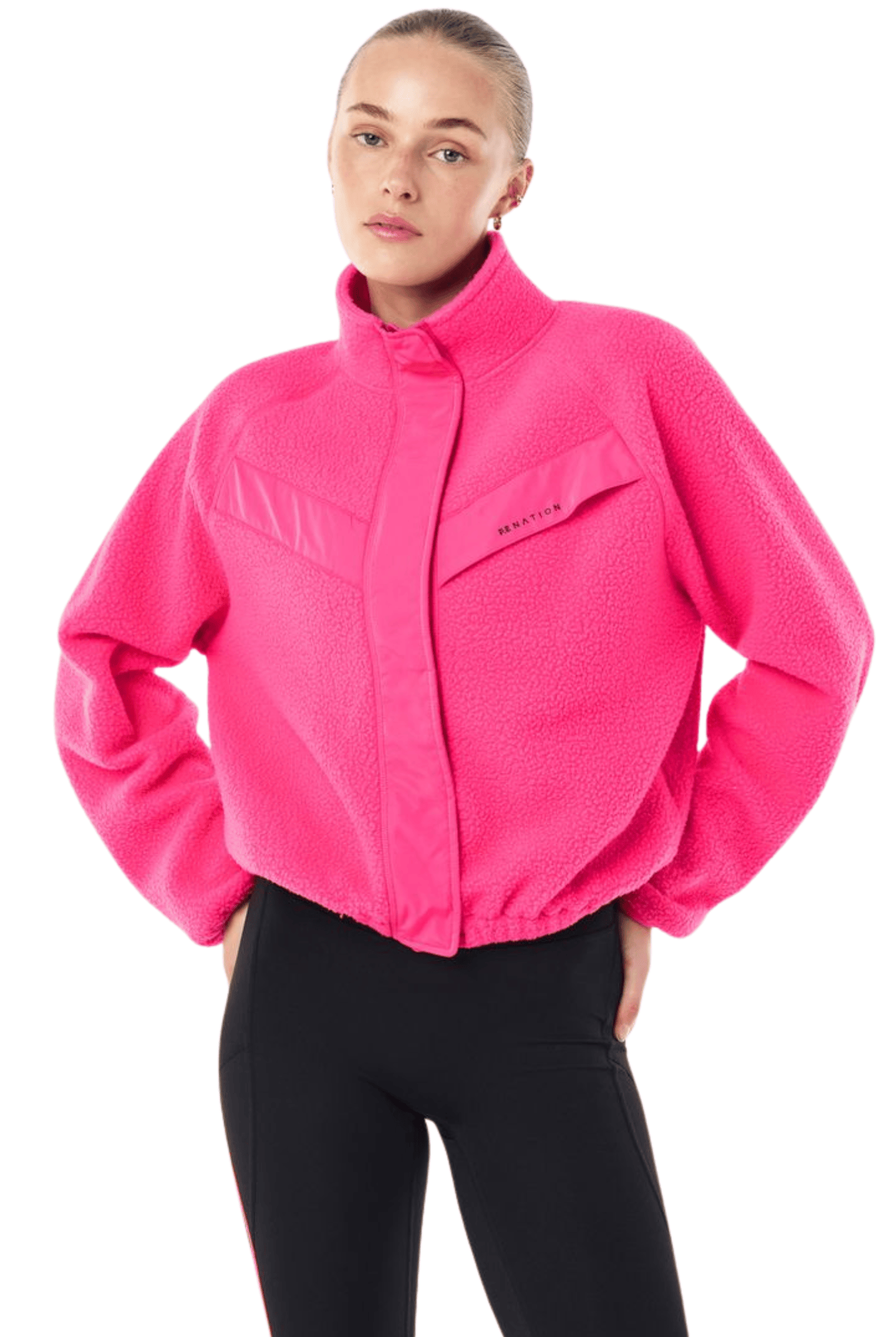 A woman modeling a bright pink fleece jacket with a stand-up collar and front zipper, paired with black pants, against a plain white background.