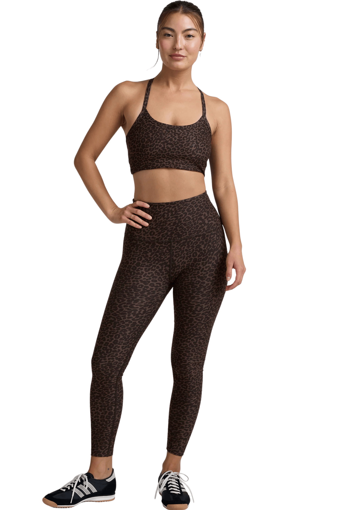 Woman wearing a patterned sports bra and leggings set on a white background