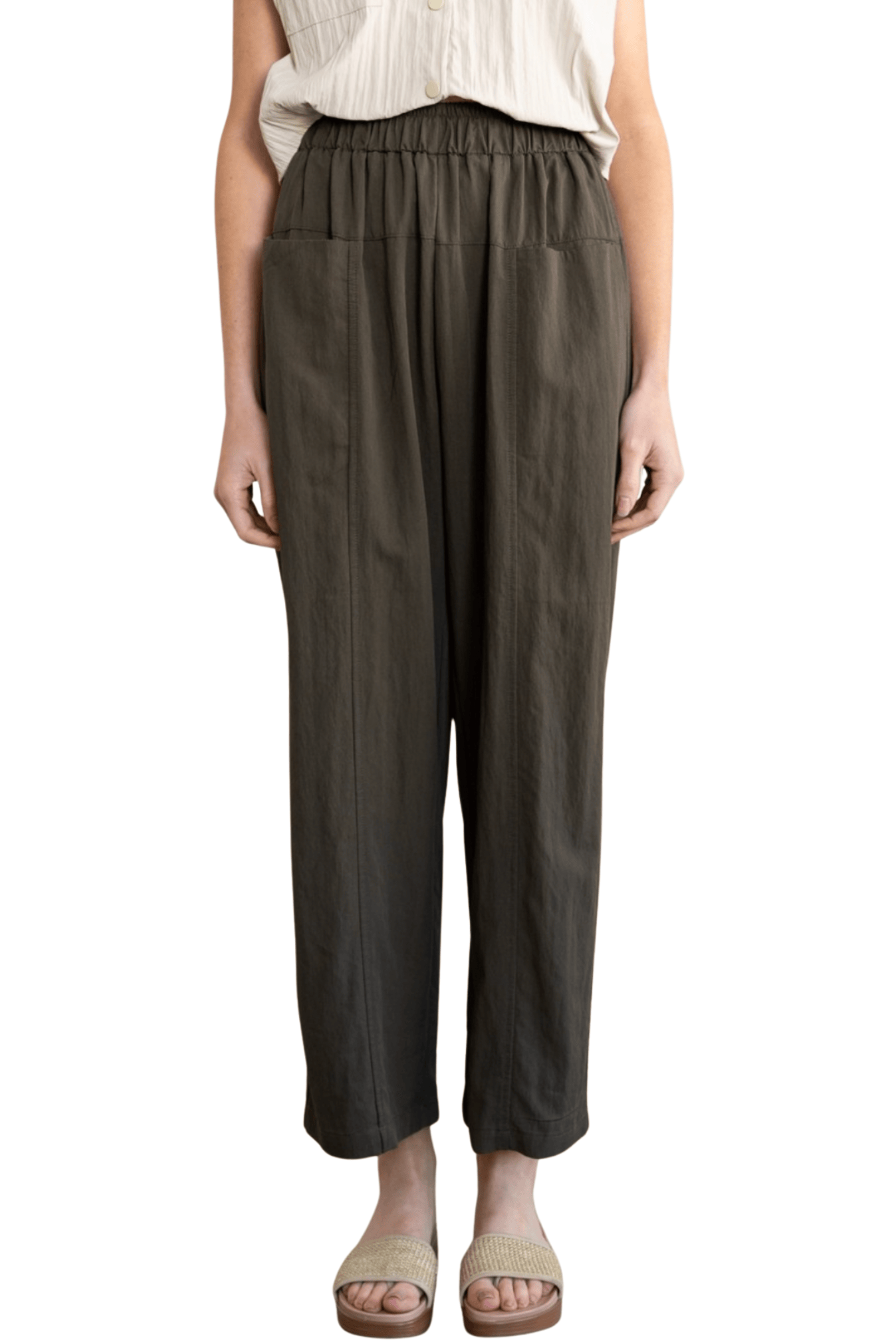 A model wearing dark olive green wide-leg cropped pants with an elastic waistband, paired with a cream-colored top and beige slide sandals, shown against a plain white background.
