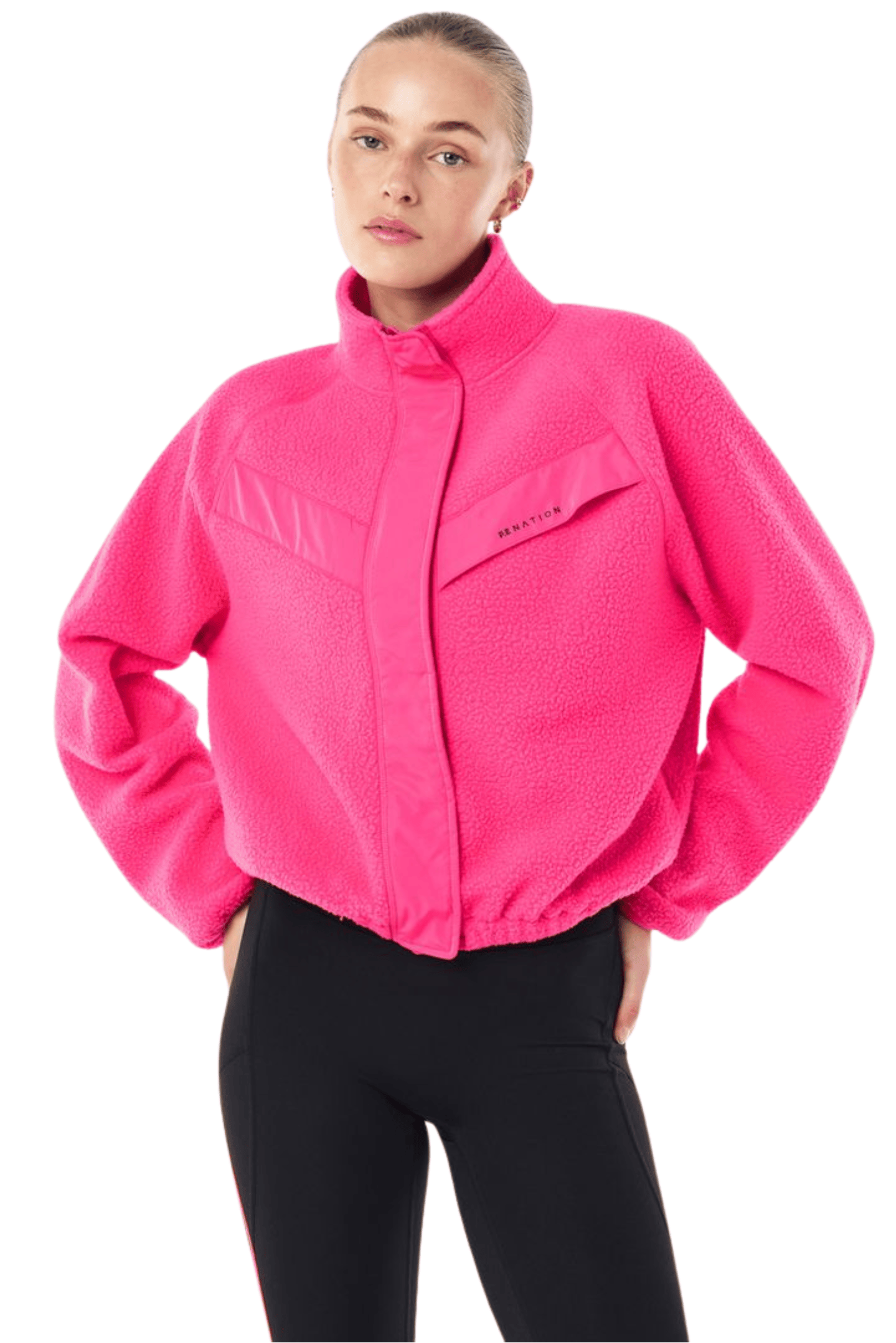 A woman modeling a bright pink fleece jacket with a stand-up collar and front zipper, paired with black pants, against a plain white background.