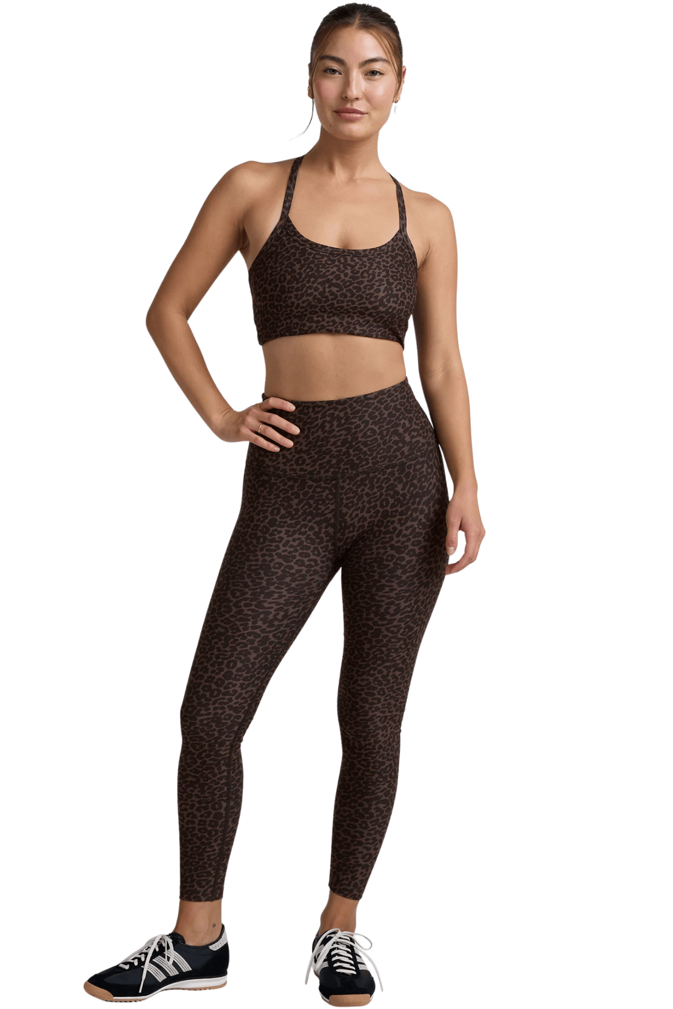 Woman wearing a patterned sports bra and leggings set on a white background